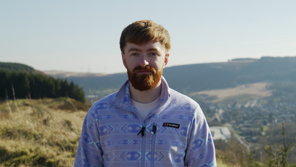 Young man looking at camera on top of a mountain on a cloudy day